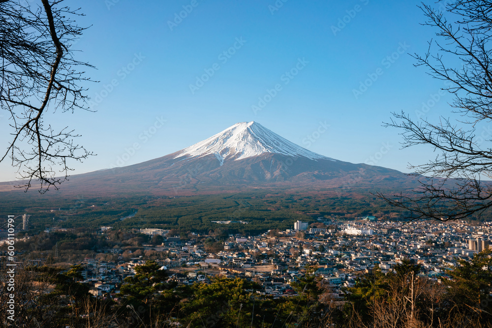 View of mount fuji with blue sky. In the foreground is a city.