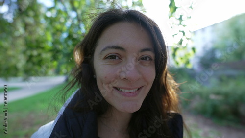 Portrait face of a woman in her 30s smiling outside standing at park. One Casual female person