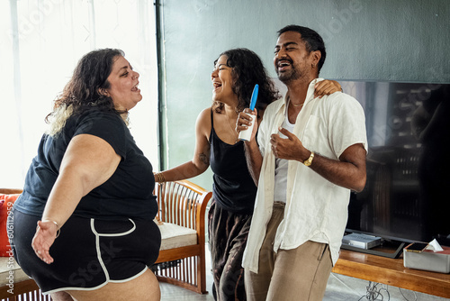 Friends dancing and singing together at home on a weekend