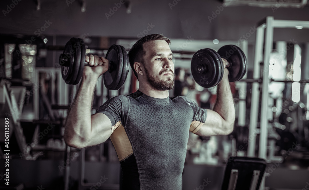 Athletic man exercising shoulder muscles with dumbbells in his hands Athletic man exercising shoulder muscles with dumbbells in his hands