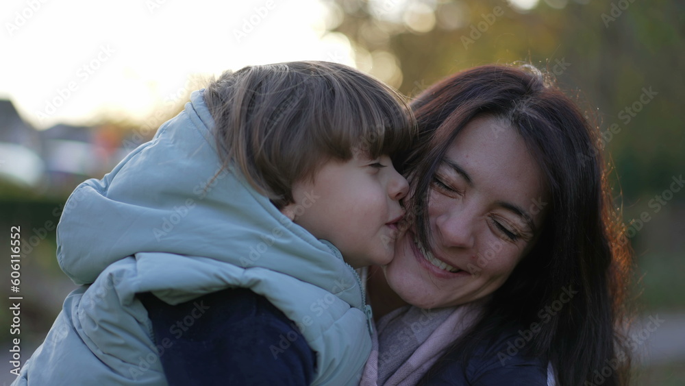 Happy mother and child relationship. Small son kissing mom in cheek. Real life moterhood