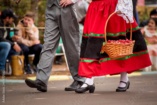 couple in old clothes parading, woman carrying basket of grapes