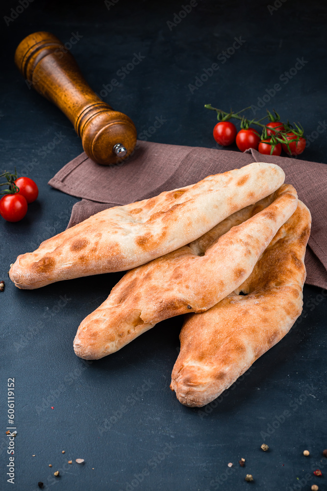 Georgian food flatbread on a dark background with cherry tomatoes. Georgian food flatbread on a dark background with cherry tomatoes.