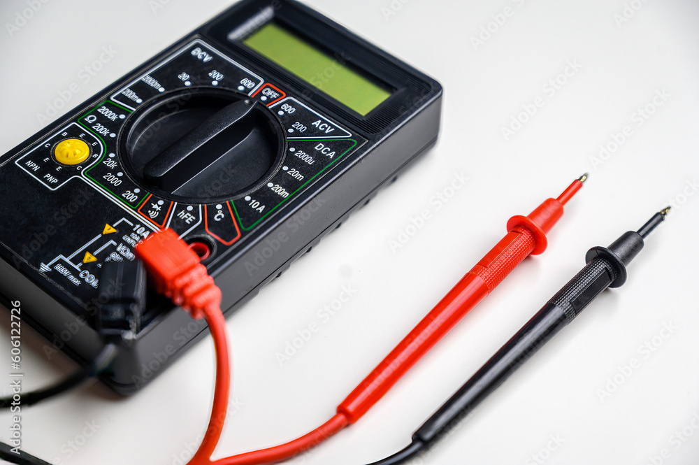 multimeter and test leads on a white table. A device for measuring current. multimeter and test leads on a white table. A device for measuring current.