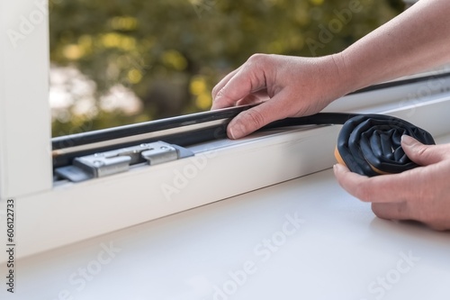 a person installing a window seal on a window. Heat saving concept.