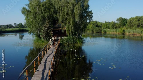 Old wooden fisherman's and hunter's house on the island. Landscape with couple in love holding hands walking on old wooden bridge to the cabin on lake. Old Solotvyn Village, Ukraine photo