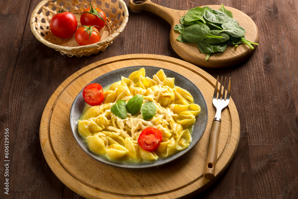 Pasta in cream sauce with cheese garnished with spinach with a fork on a round wooden stand. Pasta in cream sauce with cheese garnished with spinach with a fork on a round wooden stand.