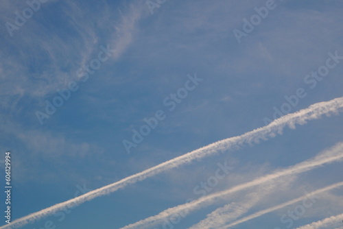 Blue sky with white fuzzy traces of clouds and plane trails background © adinamnt