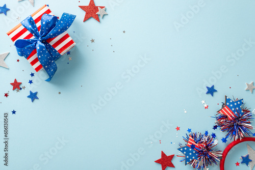 USA Independence Day motif. Top view of symbolic party props like sparkling stars  glimmering confetti  party headband  and giftbox  on pastel blue background with an empty space for text or ad