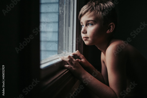 Young boy looking out the window on a rainy summers day 