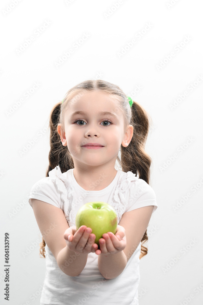 A little girl holds a green apple in her hands A little girl holds a green apple in her hands