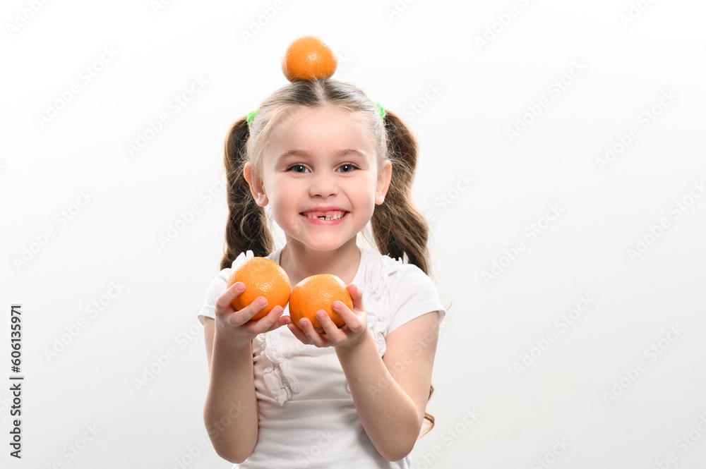 Portrait of a small beautiful girl on a white background with tangerines in her hands. Portrait of a small beautiful girl on a white background with tangerines in her hands.