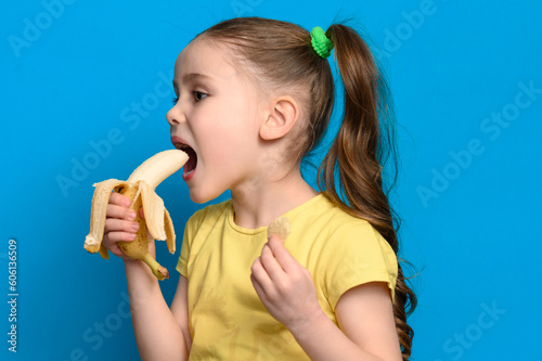 On a blue background, the girl holds one banana and potato chips in her hands.