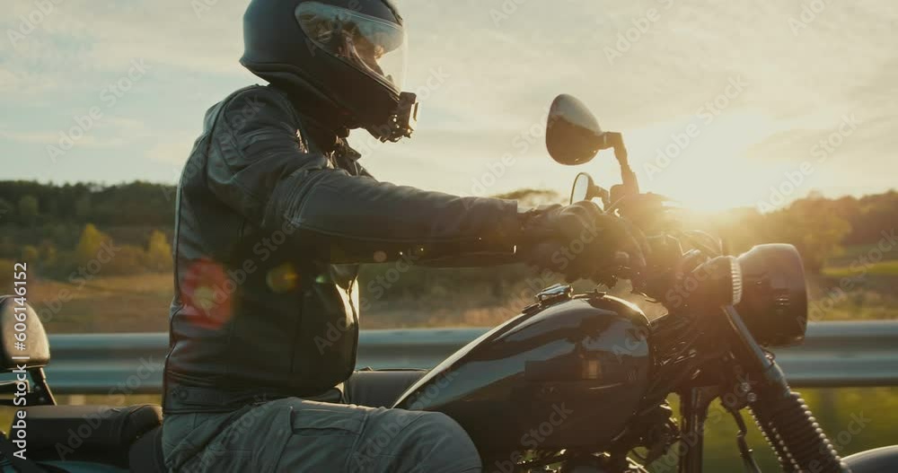 Handsome young man riding a black motorcycle during the sunset.