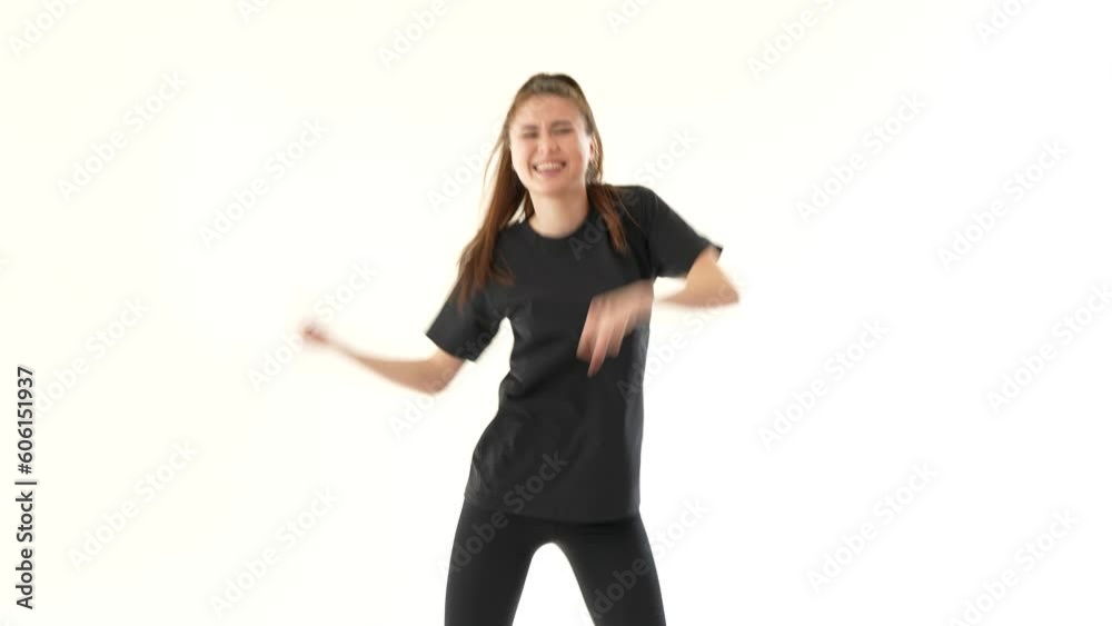 Pretty woman dancing modern dance on white wall background. She has long hair and wearing black leggings and black T-shirt. Joyful girl enjoying her favorite music. Pretty woman dancing modern dance on white wall background. She has long hair and wearing black leggings and black T-shirt. Joyful girl enjoying her favorite music.