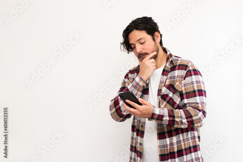 Hispanic-Arabian man looking his cell phone with pensative face and copy space