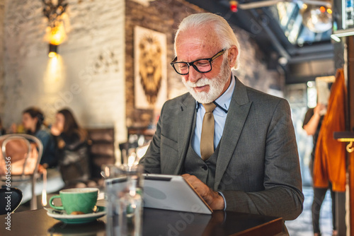 Senior man businessman business owner use digital tablet sit at cafe