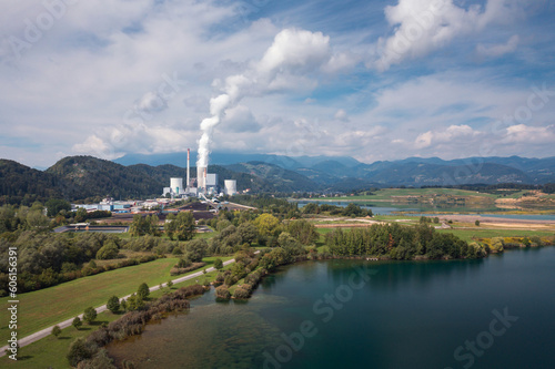 Smoking chimney at thermal power plant near lake and green nature. Aerial view