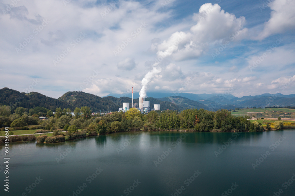 Smoking chimney at thermal power plant near lake and green nature. Aerial view