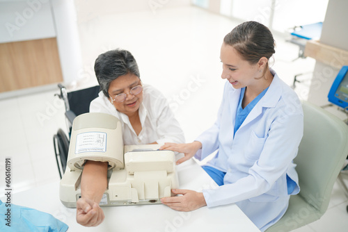 Female doctor doctor measuring senior female's blood pressure at medical clinic.