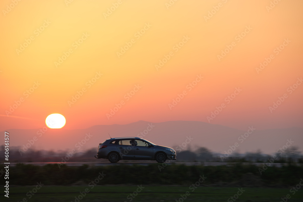 Fototapeta premium Car driving fast on intercity road at sunset. Highway traffic in evening