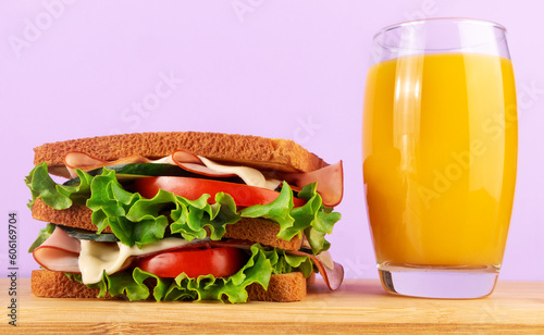 Sandwich with ham, cheese, tomato and lettuce and glass of orange juice