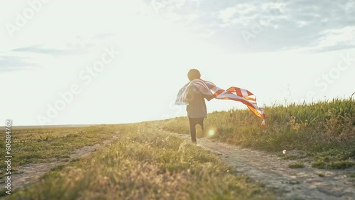 Cute little boy - American patriot kid running with national flag on open area countryside road.USA, 4th of July - Independence day, celebration. US banner, memorial Veterans, election, America, labor