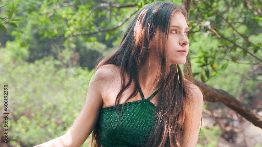 Girl looks sideways in a green swimsuit against the background of a park Girl looks sideways in a green swimsuit against the background of a park