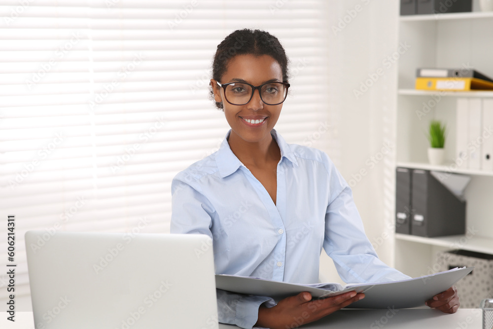 African American intern with folder working at white table in office African American intern with folder working at white table in office