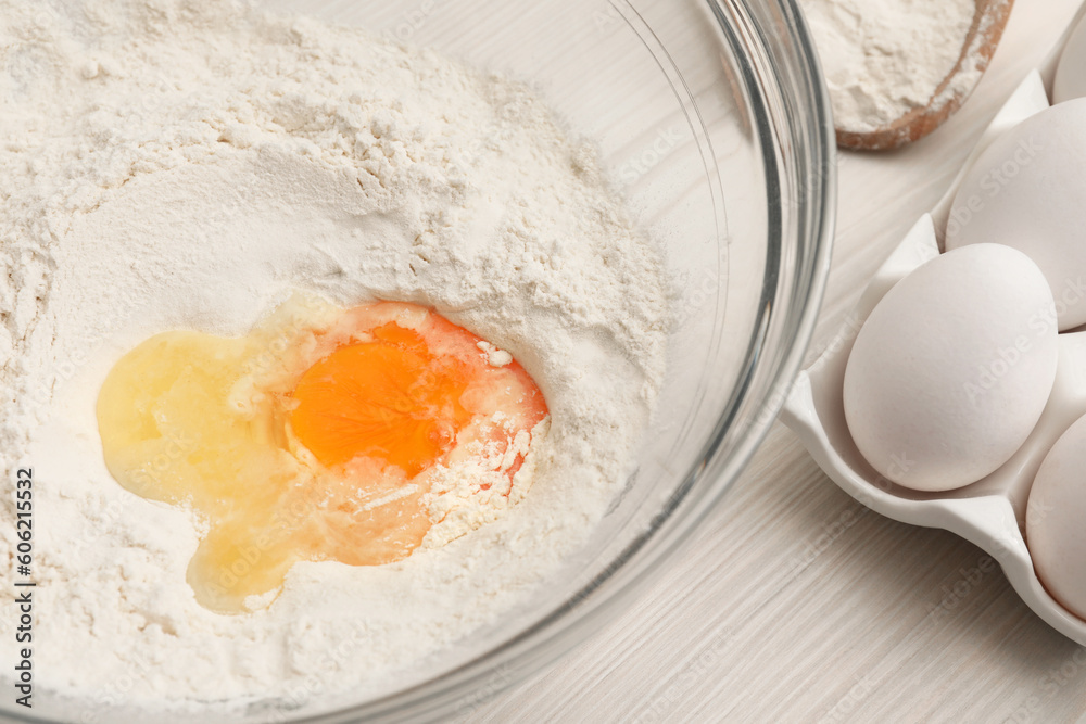 Bowl with flour and egg on white wooden table, closeup Bowl with flour and egg on white wooden table, closeup