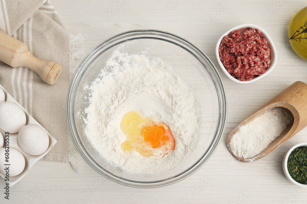 Bowl with flour, egg and products on white wooden table, flat lay Bowl with flour, egg and products on white wooden table, flat lay