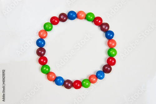 Skittles sugar candy in a circle with variety of colors from red and blue and violet and purple and orange and green on a white background