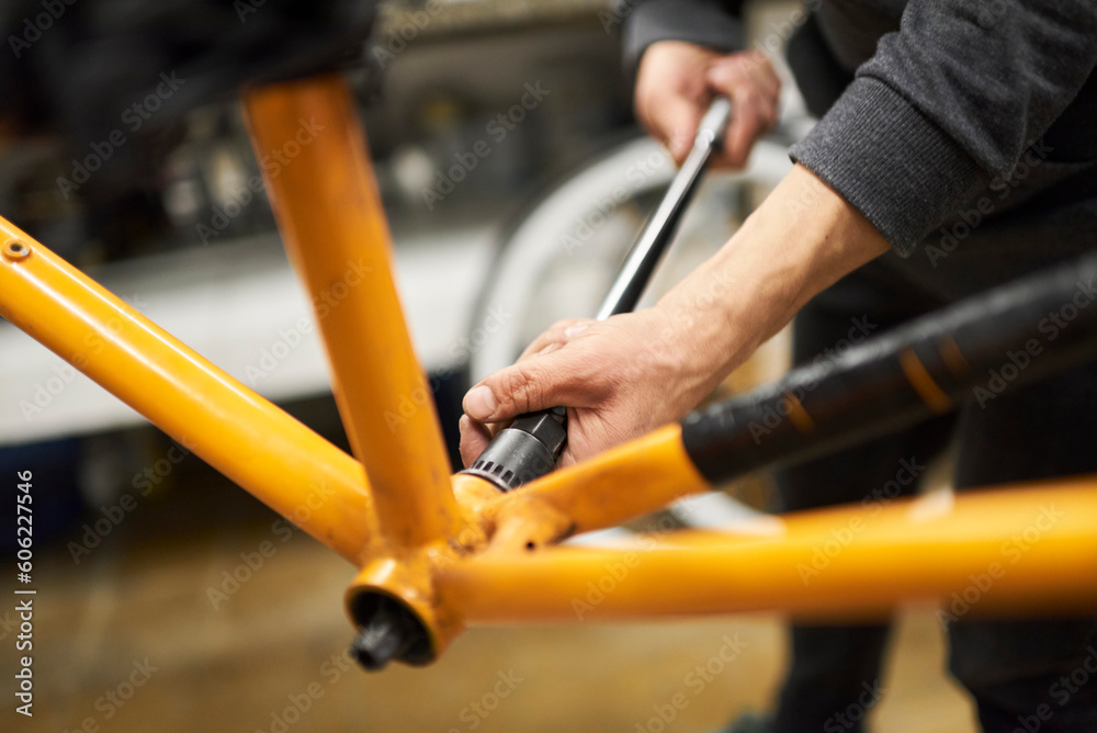 Unknown man disassembling an orange bike to paint it, change the color of the frame, at his repair shop.