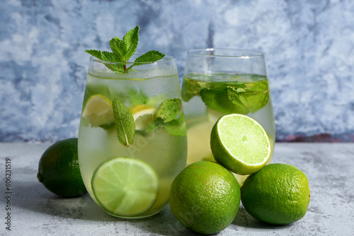 Glasses of cold mojito and lime on blue table
