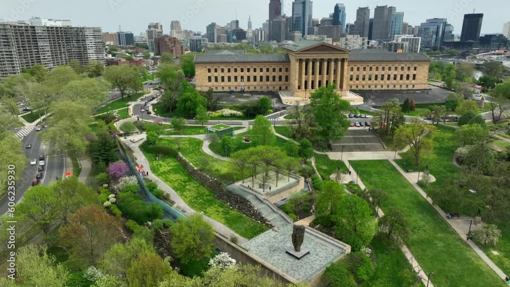 Aerial rotation around Philadelphia Museum of Art and Fairmount Park. City skyline and blue sky behind lush urban green spaces and public musuem in historic city of brotherly love.