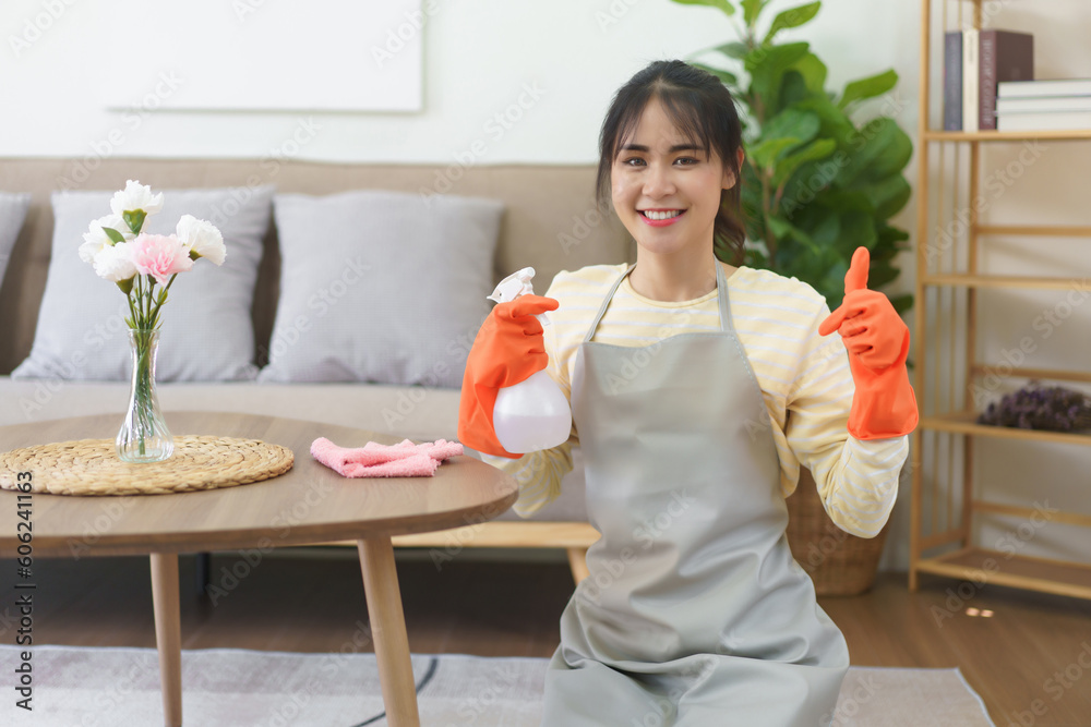Maid holding spray cleaner bottle and showing thumb up after cleaning and wiping the dirty in home Maid holding spray cleaner bottle and showing thumb up after cleaning and wiping the dirty in home