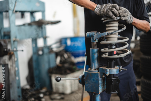 Auto mechanic installing coil springs into shock absorber struts. photo