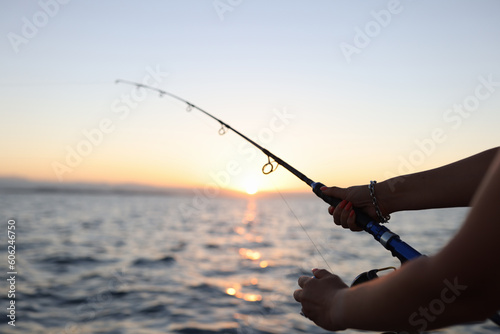 Obraz na płótnie Woman enjoys fishing on boat sailing in sea at sunset w salonie
