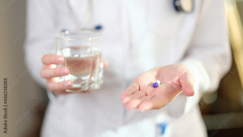 Doctor in uniform holds pill and glass of water in hands Doctor in uniform holds pill and glass of water in hands