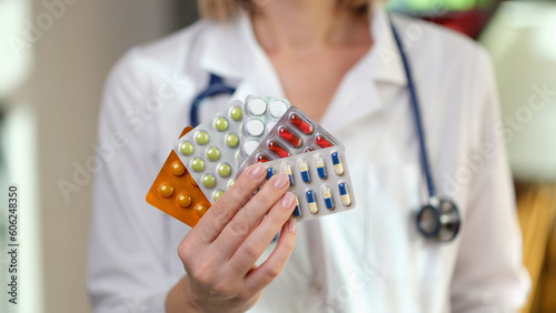 Nutritionist holds fan of different pills in hand in clinic