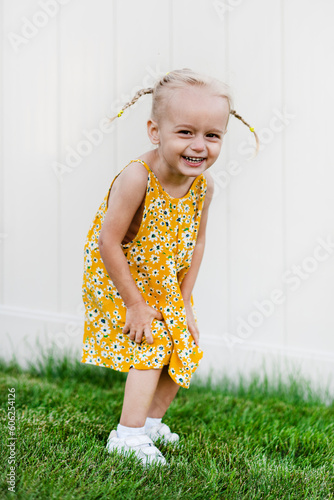 Little beautiful girl posing in summer dress on green grass and white background