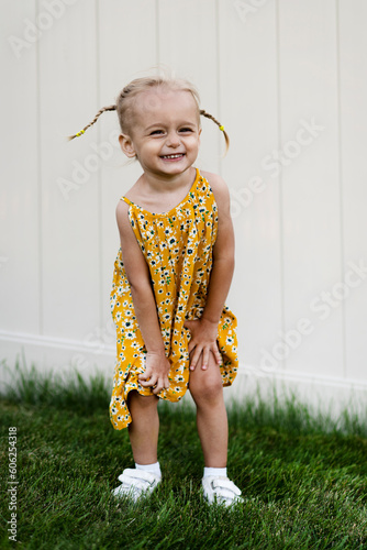 Little beautiful girl posing in summer dress on green grass and white background
