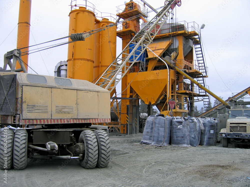 yellow asphalt plant produces asphalt on a cloudy day