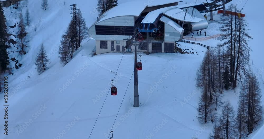 Overhead drone shot of operating ski lift above the snow-covered slope and quaint ski resort in Val Gardena, Dolomites. Overhead drone shot of operating ski lift above the snow-covered slope and quaint ski resort in Val Gardena, Dolomites.