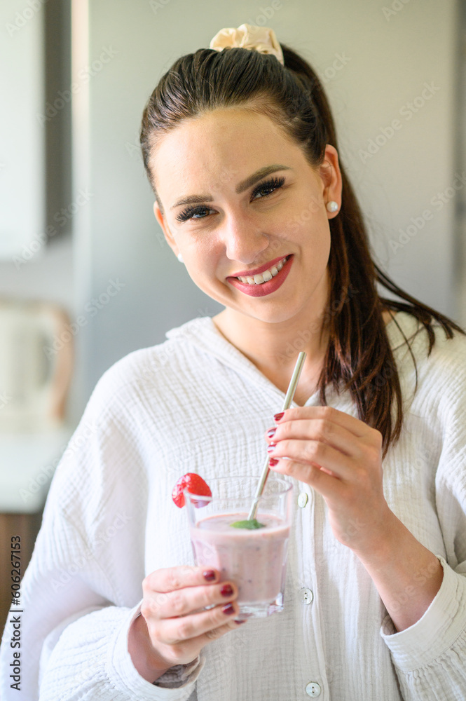 Smiling woman standing with glass of smoothie and straw Smiling woman standing with glass of smoothie and straw