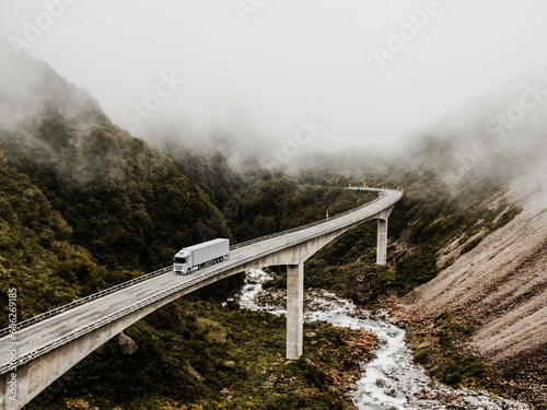 Semi-Truck and Trailer Crossing Majestic Mountain Bridge