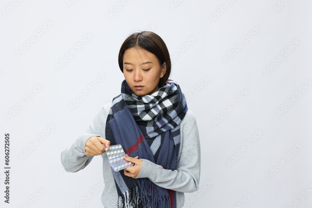 Asian woman headache cold flu holding medicine and pills with fever is sick from the virus on a white background, copy space Asian woman headache cold flu holding medicine and pills with fever is sick from the virus on a white background, copy space