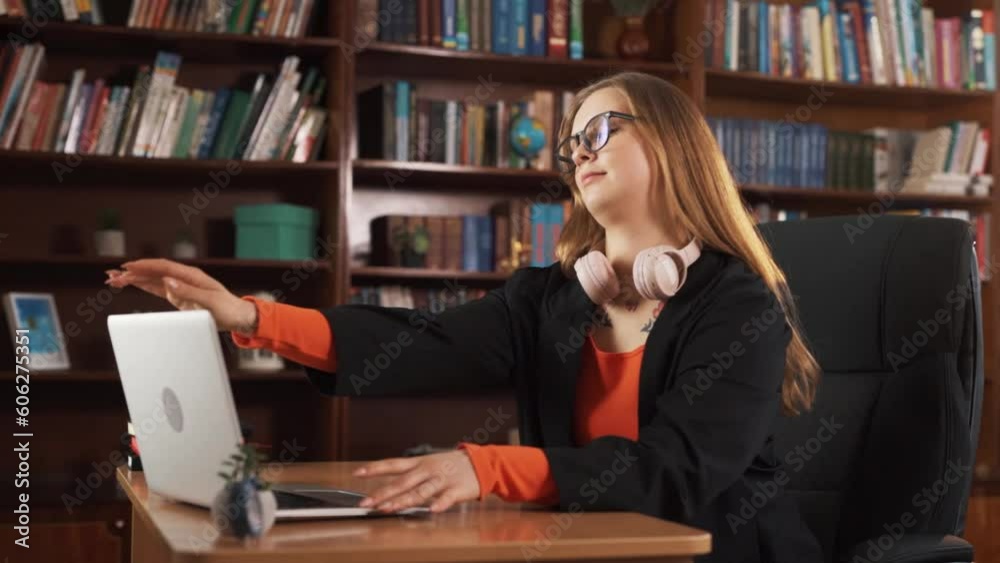 The girl is sitting at her desk, working and typing something on her laptop. She closes the laptop leans back in her chair takes off her glasses, and enjoys the satisfaction of the end of the workday. The girl is sitting at her desk, working and typing something on her laptop. She closes the laptop leans back in her chair takes off her glasses, and enjoys the satisfaction of the end of the workday.