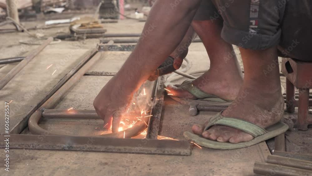 Rudimentary man welding a dress stand in an underdeveloped factory in Bangladesh Rudimentary man welding a dress stand in an underdeveloped factory in Bangladesh