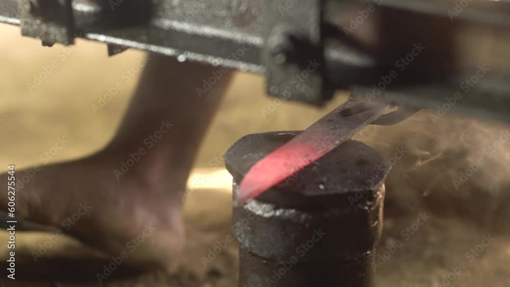 Man hammering an incandescent knife to shape with semi automatic blacksmith. Close up Man hammering an incandescent knife to shape with semi automatic blacksmith. Close up